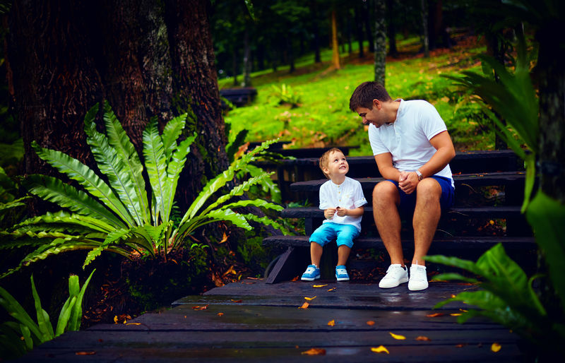 快乐的父子坐在雨林的木楼梯上