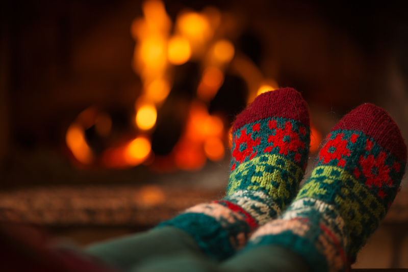 袜子上的袜子-女人用温暖的炉火放松-用袜子暖脚-靠近脚-冬季和圣诞节假期的概念