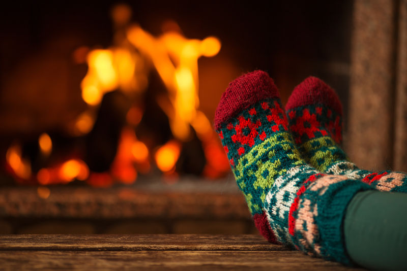 袜子上的袜子-女人用温暖的炉火放松-用袜子暖脚-靠近脚-冬季和圣诞节假期的概念