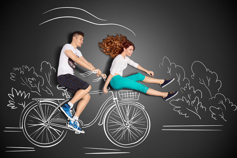快乐情人的爱情故事概念-一对浪漫的情侣在粉笔画的背景下-男骑女朋友在前自行车篮里