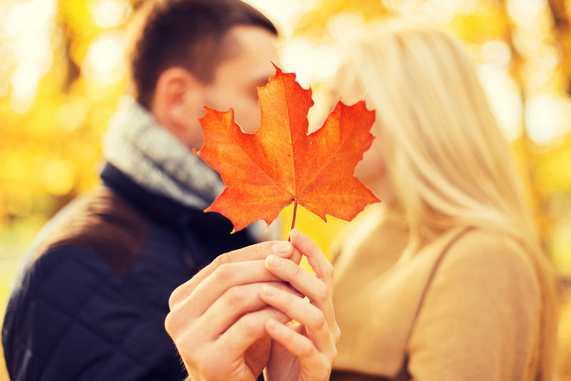爱情、关系、家庭和人的概念——秋园枫叶亲吻情侣特写