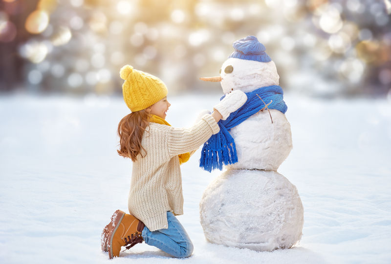 在大自然的冬日散步中与雪人玩耍的快乐女童