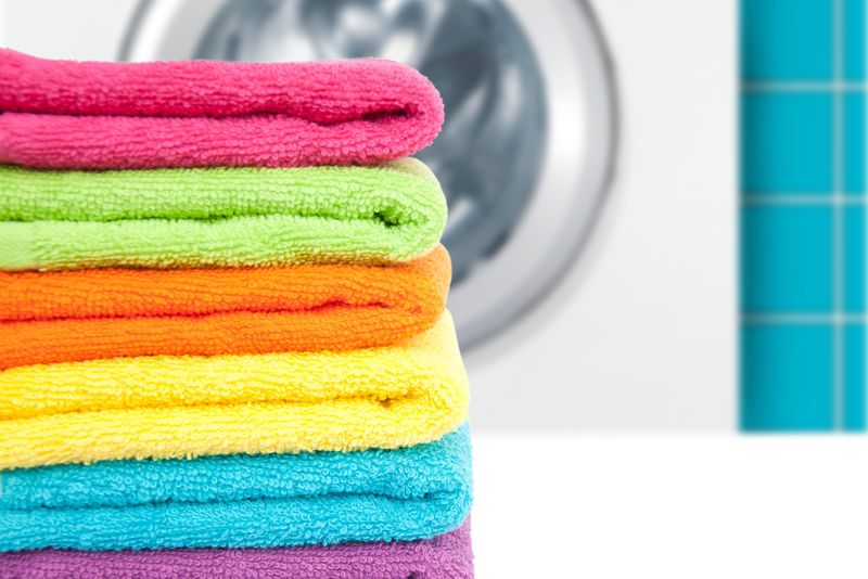 一堆彩色干净毛巾和洗衣机
