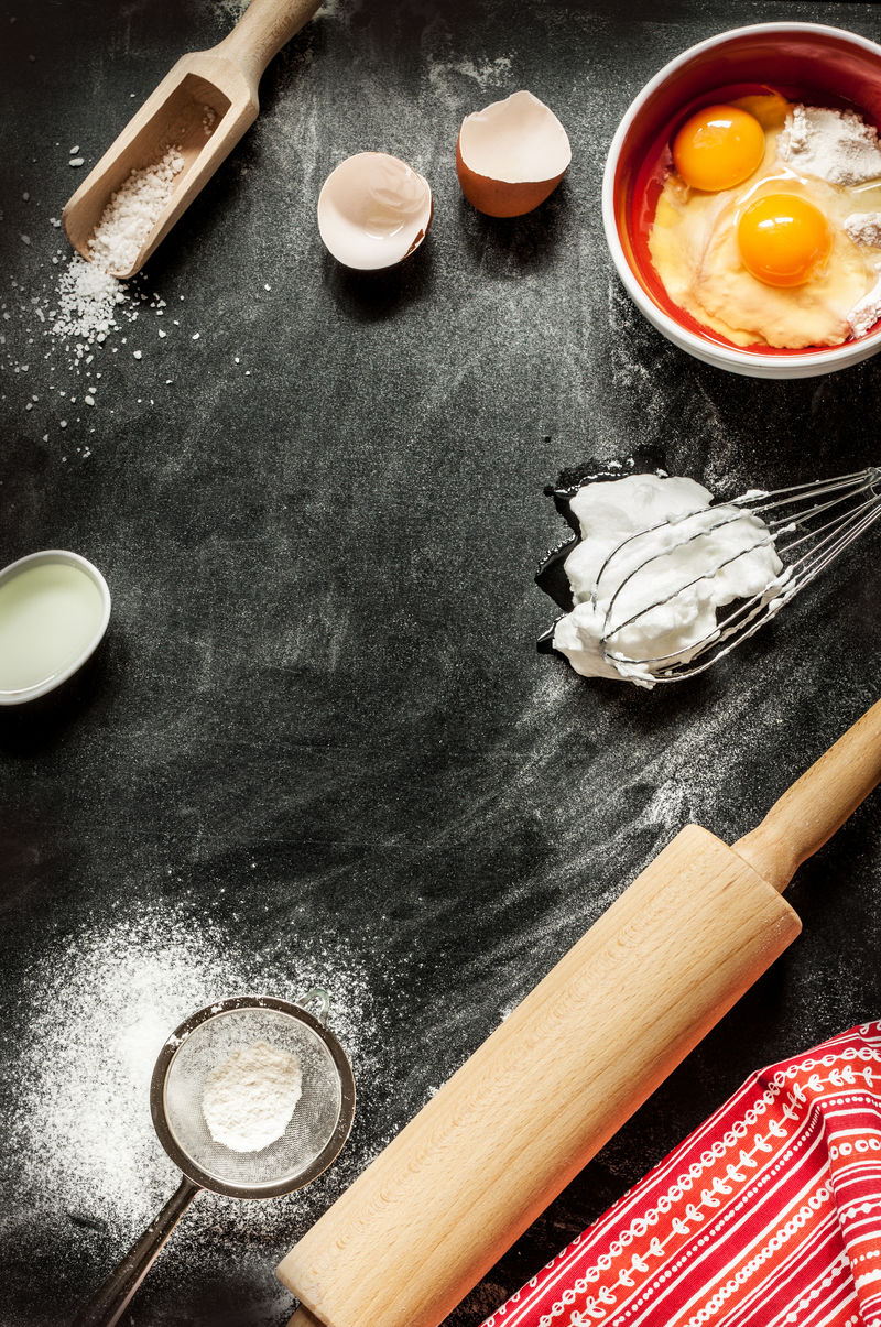 烘焙蛋糕配料-碗-面粉-鸡蛋-蛋清泡沫、打蛋器、擀面杖和蛋壳上黑色的黑板-烹饪课程海报背景-布局与文本空间