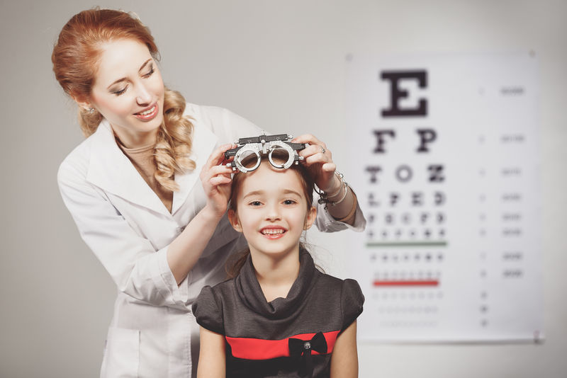 年轻的女孩微笑而发生与综合验光仪检测眼睛