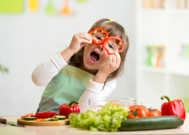 小女孩在厨房吃蔬菜玩得很开心