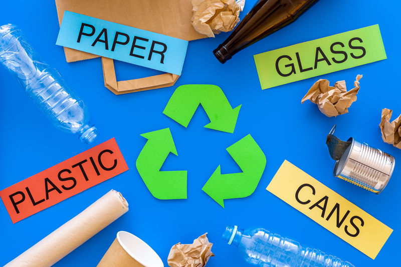 适用于绿色循环生态符号附近循环使用的材料-文字纸、玻璃、塑料、蓝色背景的罐子俯视图