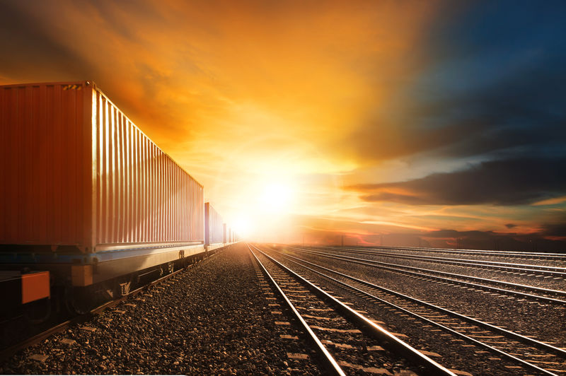铁路轨道上的工业集装箱列车在美丽的阳光下行驶-用于陆路运输和物流业务