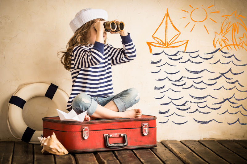 快乐孩子在室内玩玩具帆船-旅行与冒险概念