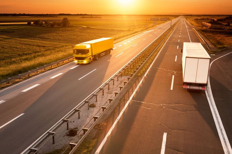日落时分-黄色和白色的卡车在高速公路上行驶
