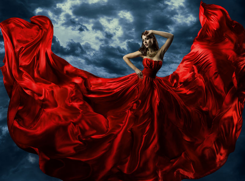 穿红色晚礼服的女人-在天空的背景下挥舞长裙