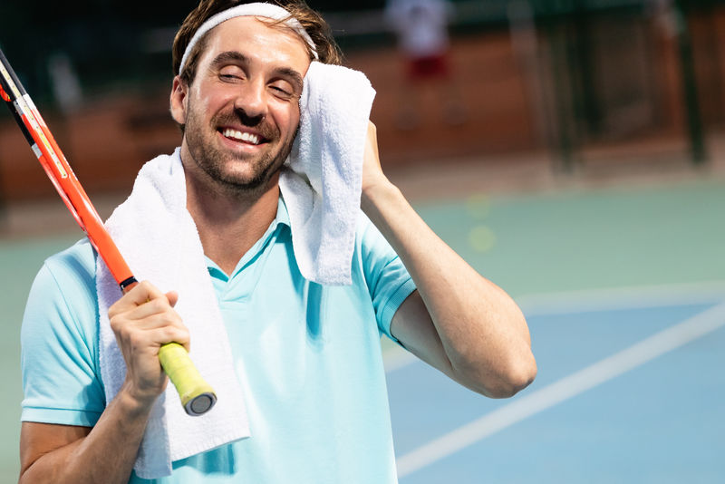 在网球场训练后用毛巾打累了的网球运动员