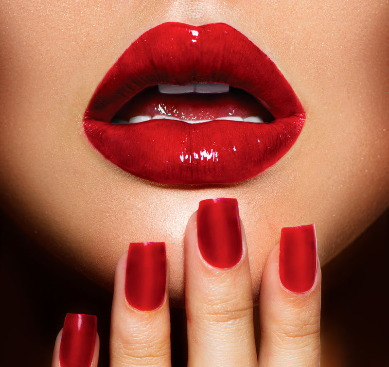 红色性感的嘴唇和指甲特写。美甲和化妆