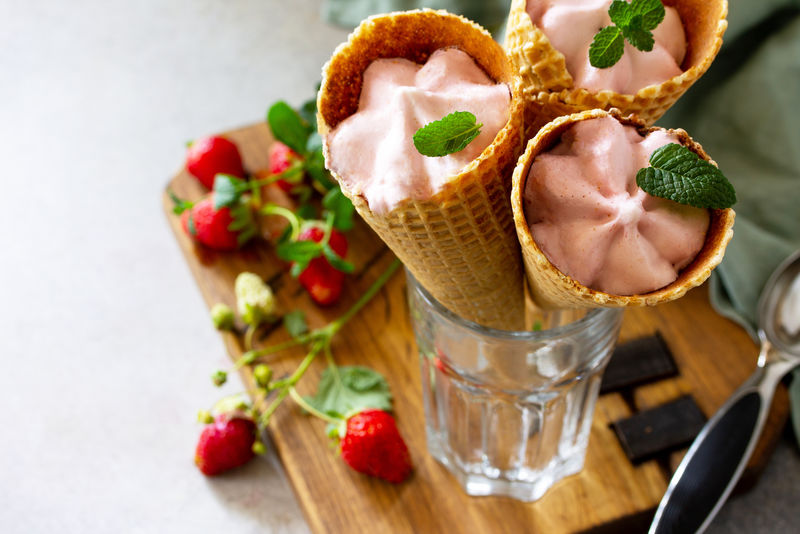 草莓冰淇淋舀成圆锥形放在轻石桌或石板桌上。为您的文本腾出空间。
