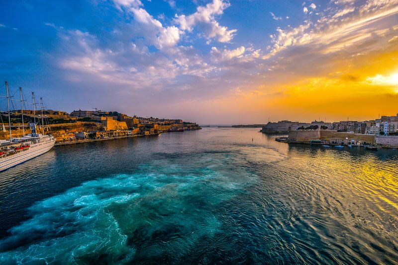 马耳他瓦莱塔大港口日出-太阳直射古城和一艘小型游轮