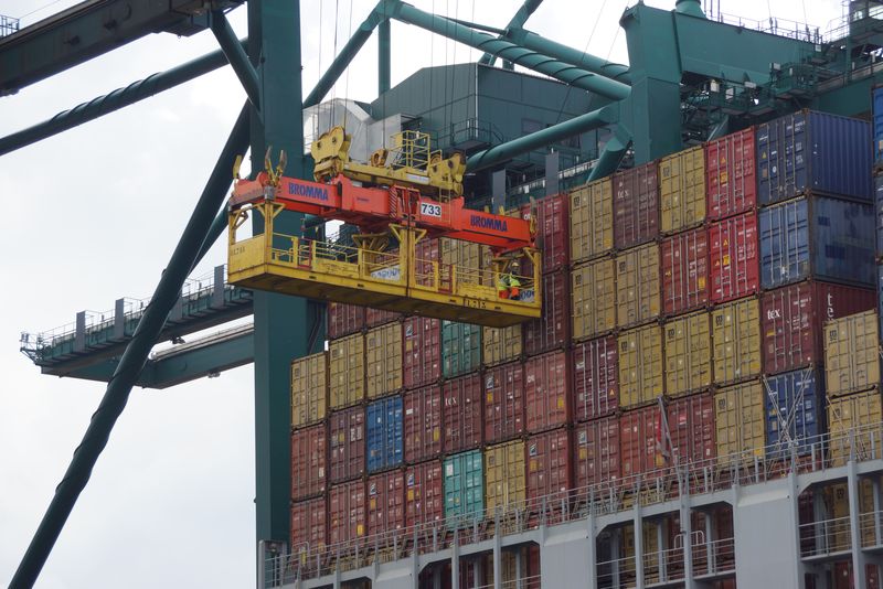 用工业起重机在货船上装载集装箱-进出口集装箱船业务物流公司-工业和交通概念