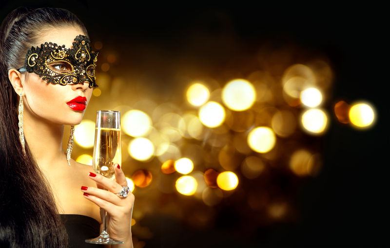性感模特女人带着香槟酒戴着假面舞会面具