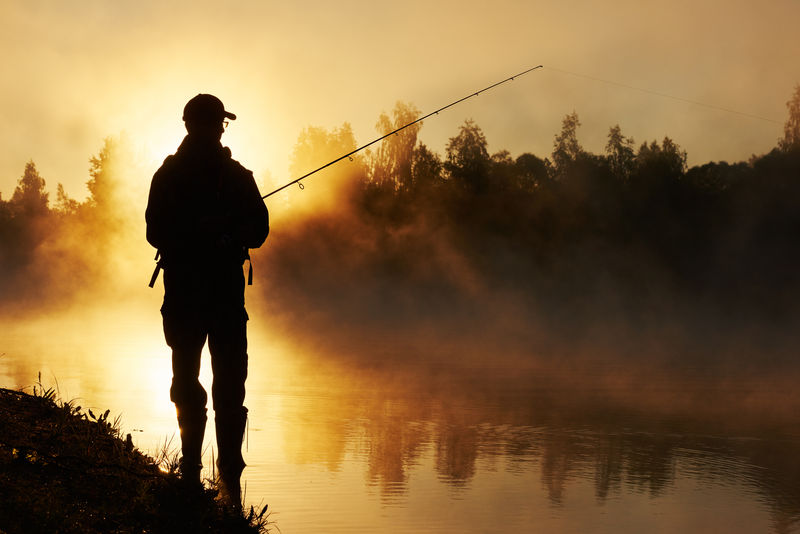 雾霾日出的渔民捕鱼
