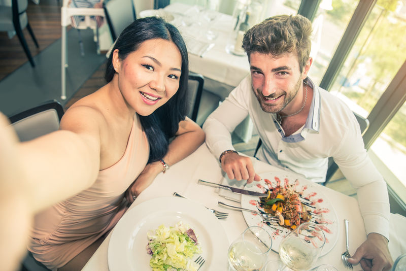 一对情侣在餐馆里拍照-日落时分在一家高档餐馆里浪漫约会-两个迷人的朋友在小酒馆里玩得很开心