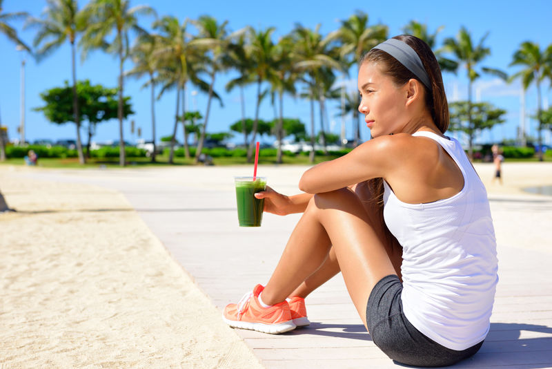 健康女跑步者喝绿色冰沙