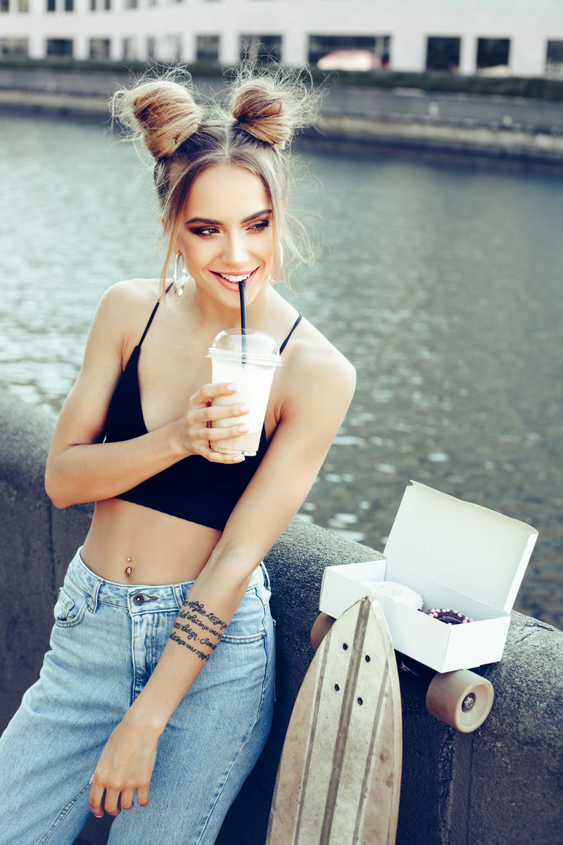 在城市街道上喝咖啡的年轻时髦女人