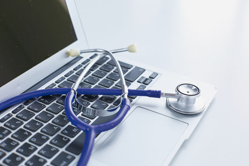 听诊器放在笔记本电脑键盘上-用于在线医疗或故障排除-从低角度看-使用复印空间