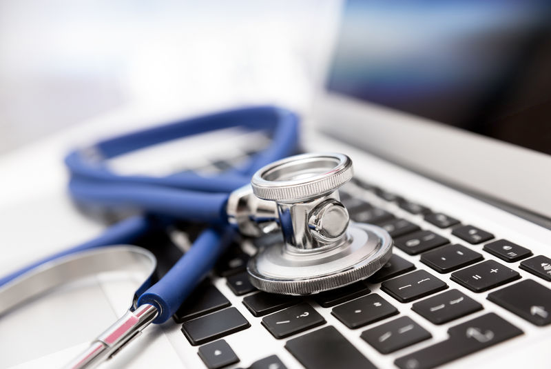 笔记本电脑键盘上的听诊器-医疗或IT安全概念