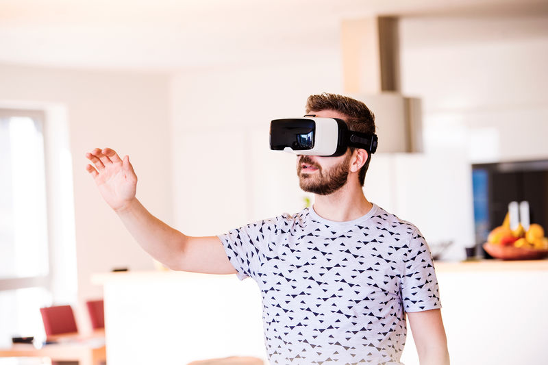 一个戴着虚拟现实眼镜的男人，站在客厅里