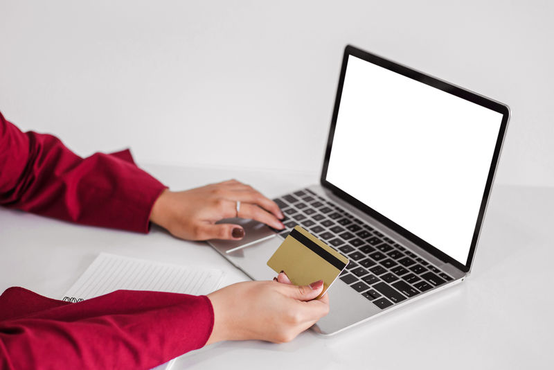 持信用卡使用笔记本电脑和电脑进行网上购物的年轻女子