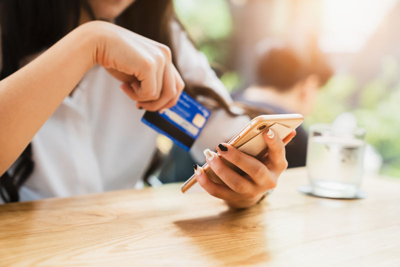 在线支付或移动互联网银行概念-女性手持智能手机购物和信用卡订单交易