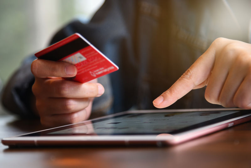 女性手持信用卡-使用笔记本电脑进行网上购物支付