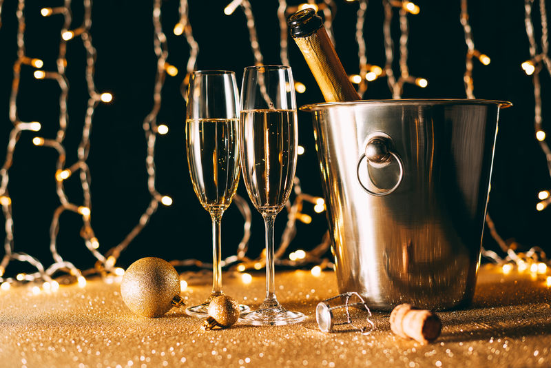 两个酒杯和一桶香槟酒-背景为花环灯-圣诞节概念