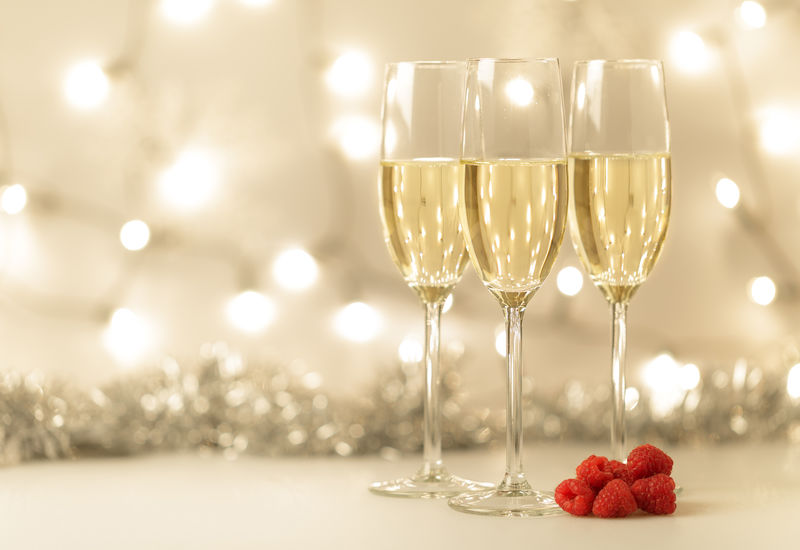 圣诞背景-优雅的香槟长笛和闪烁的灯光-装饰-新鲜的覆盆子-为您的节日愿望复制空间