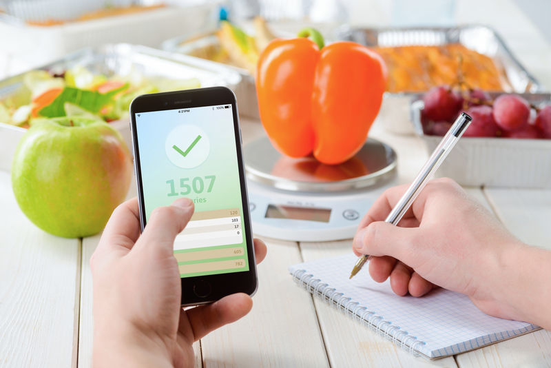 健康饮食-节食-科技-食物和人的概念-在家里用智能手机吃蔬菜沙拉的年轻女性特写