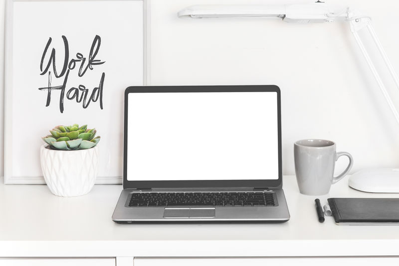 笔记本电脑工作台前视图为白色空白屏幕-办公桌上有多汁的花朵