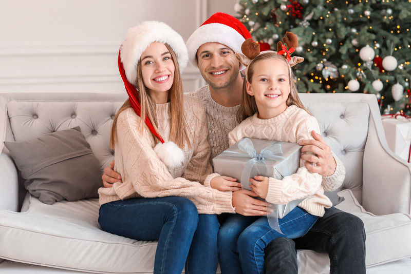 快乐家庭母亲父亲和孩子在圣诞节早上在床上穿着睡衣打开礼物