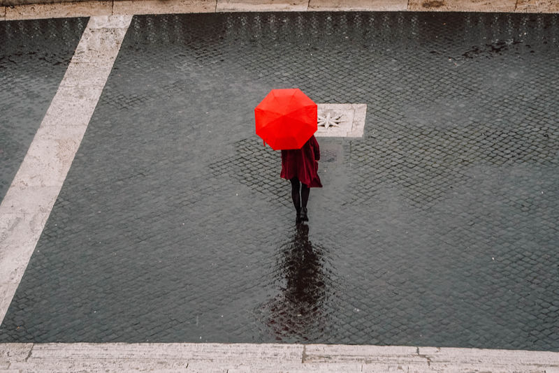 穿红色外套的女人在走过的时候拿着红色的雨伞