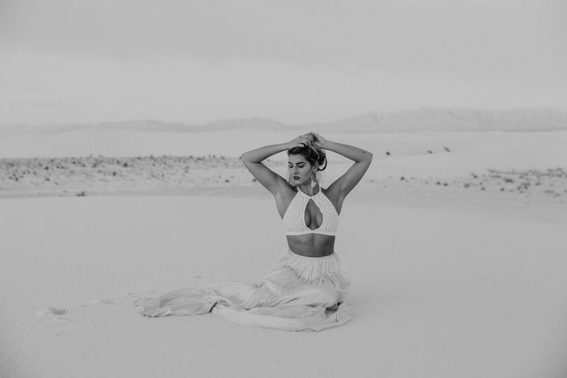 坐在沙漠上的女人的灰度照片