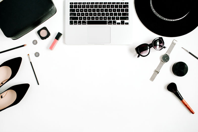 时尚博客办公桌-白色背景-配有笔记本电脑和黑色女装及配饰收藏-平放-俯视图