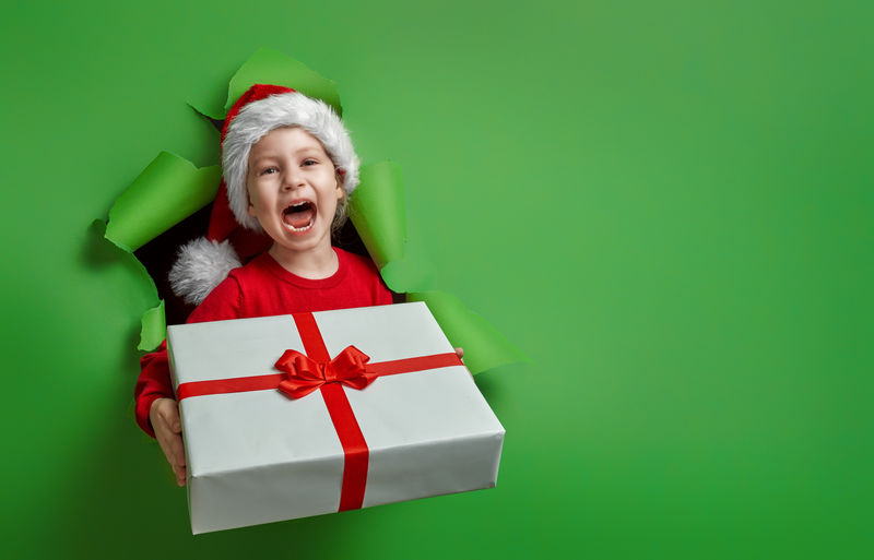 快乐的小女孩-在明亮的颜色背景上带着圣诞礼物-红色和绿色