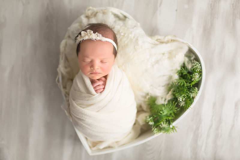 第一次拍照-新生儿-新生儿-孩子躺在白色的心脏里-初生女孩