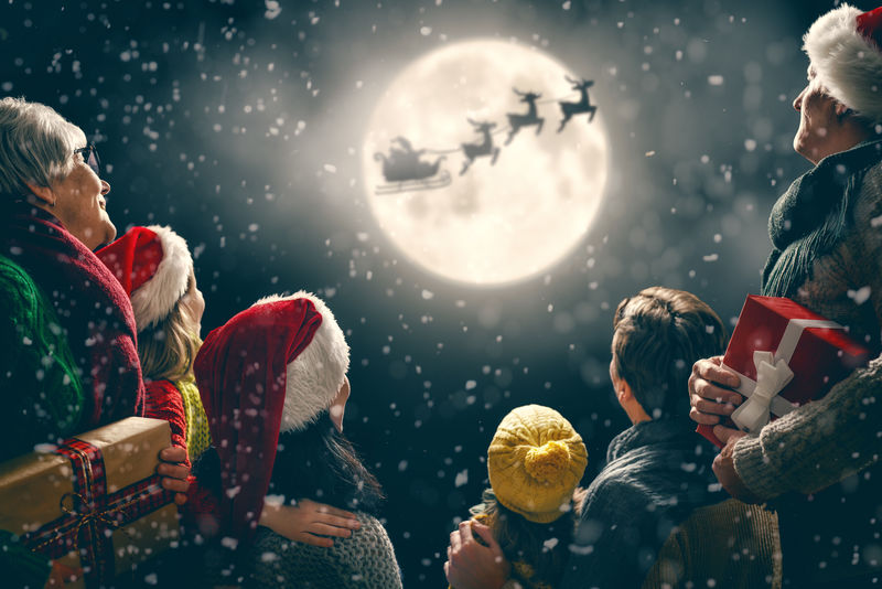 圣诞快乐-节日快乐！有妈妈-爸爸-奶奶和爷爷的可爱的孩子们-圣诞老人驾着雪橇飞向月亮的天空-一家人在黑暗的背景下享受假期