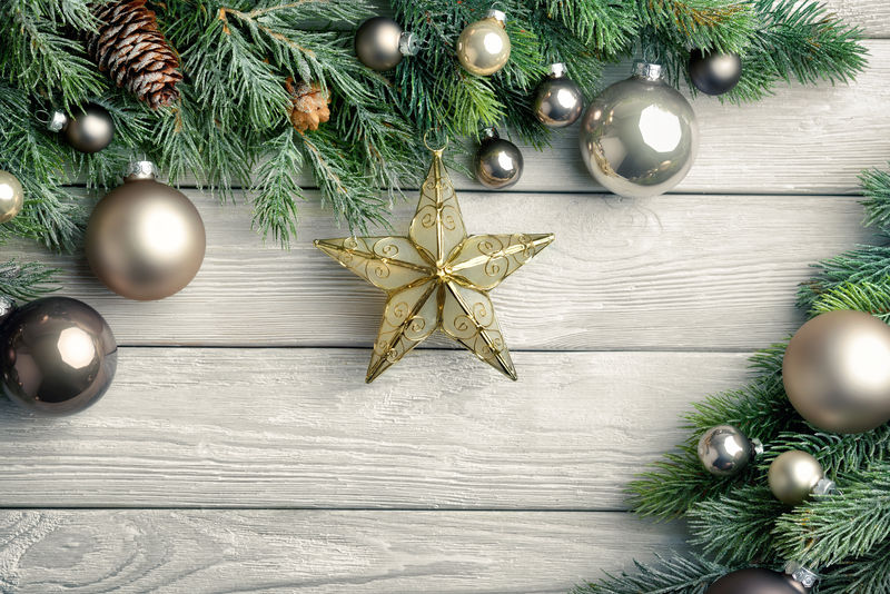 圣诞背景用明亮的木板和杉木树枝装饰着银色的饰品和一颗金星-现代-简单而优雅