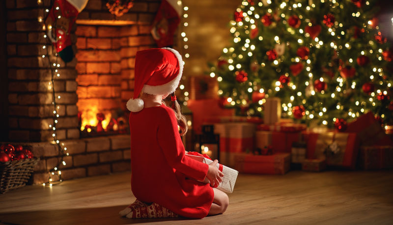 圣诞前夜-圣诞树前坐着一个快乐的小女孩-带着神奇的礼物