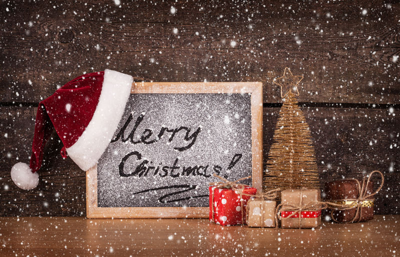 黑板上用粉笔写的问候语和木制背景上的圣诞装饰品