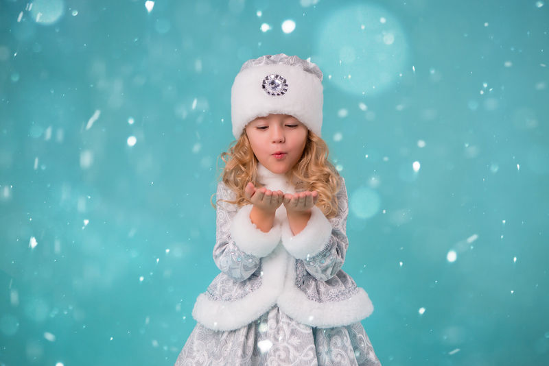 金发碧眼的小女孩-穿着雪地少女装-在蓝色的背景下微笑着-宝宝抓到了雪花