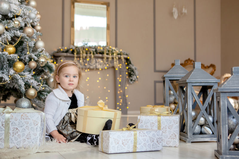 微笑可爱的小女孩打开圣诞礼物，背景