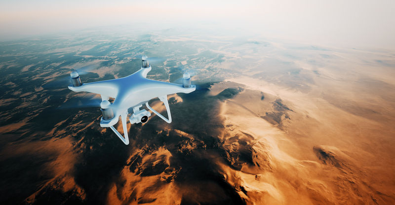 图为白色哑光通用设计空中无人机在地表下飞行。无人居住的沙漠山脉日落背景。水平，前顶角视图。电影效果。三维渲染。