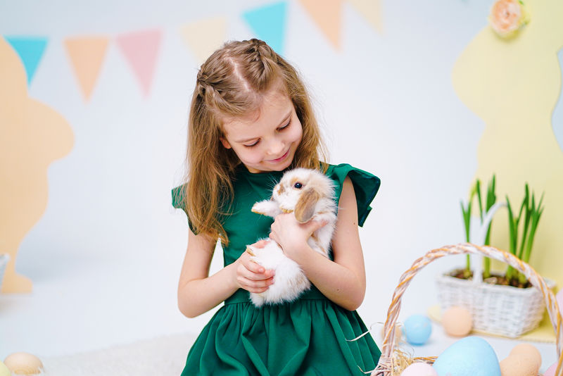 带兔子的女孩。快乐的小女孩抱着可爱的毛茸茸的兔子。与复活节兔子的友谊。春天与美丽的小女孩和她的兔子合影。女孩抱着一只可爱的小兔子