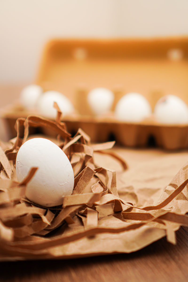 复活节，棕色纸上的白鸡蛋和木制小报上的蛋盘